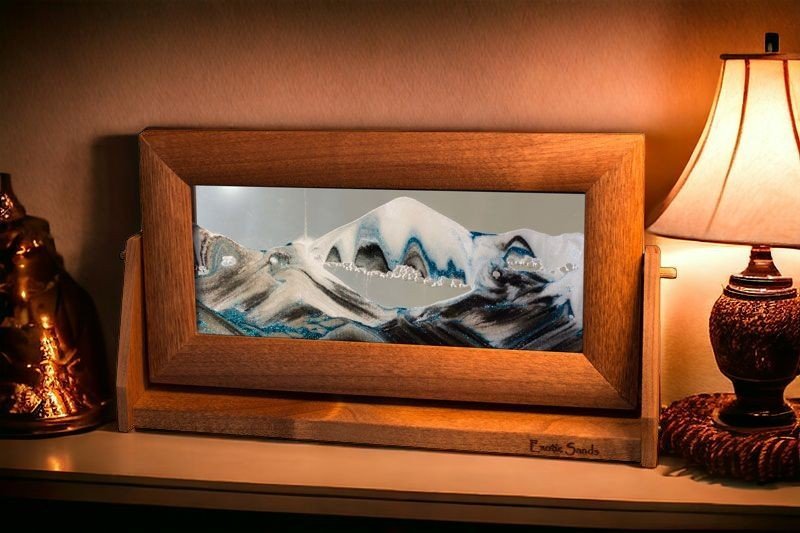 Sandscape Sand Art in an alder wood frame and swivel stand with clear liquid, ever-changing black & white sands accented with blue glitter. Enhances any shelves.