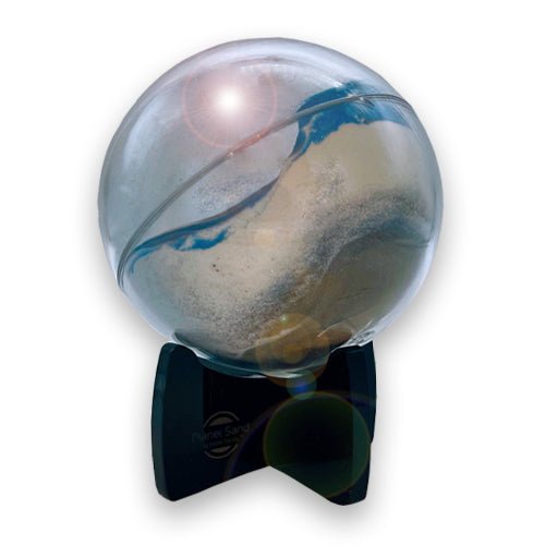 A Planet Sand Globe with dry-sifted black and white sands and shimmering blue glitter, displayed on a black easel stand. Moving sand art piece made in America.