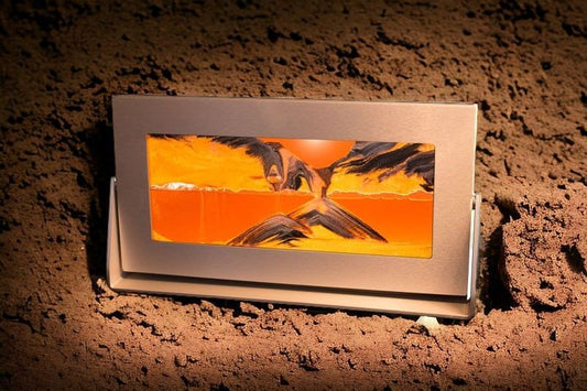 A sifting sandscape art by Exotic Sands in a silver metal frame showcases a mountainous landscape with black and white sands moving sand art pictures