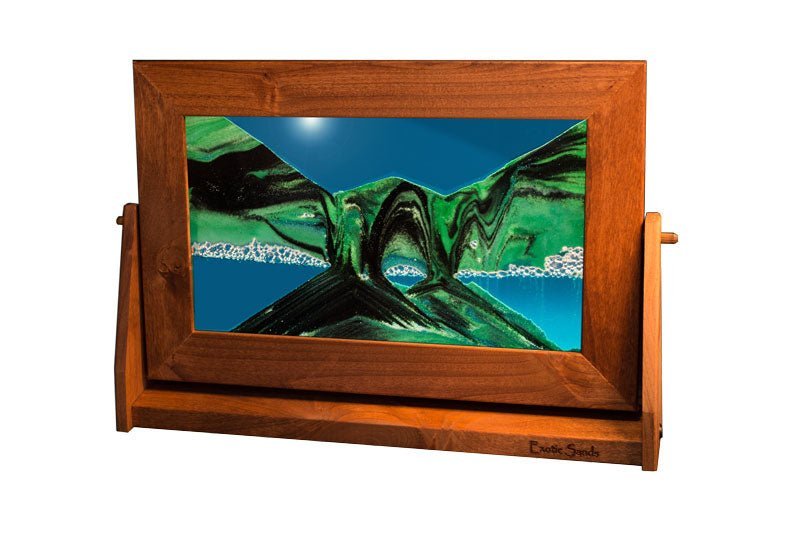 Wood-framed sandscapes piece with colored layers of sands forming mountain-like patterns against a blue liquid background.